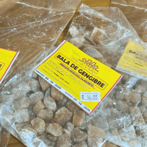 Pacotes de plástico transparente com Balas de Gengibre artesanais cobertas com açúcar, exibindo o rótulo amarelo da marca Sítio do Campo.