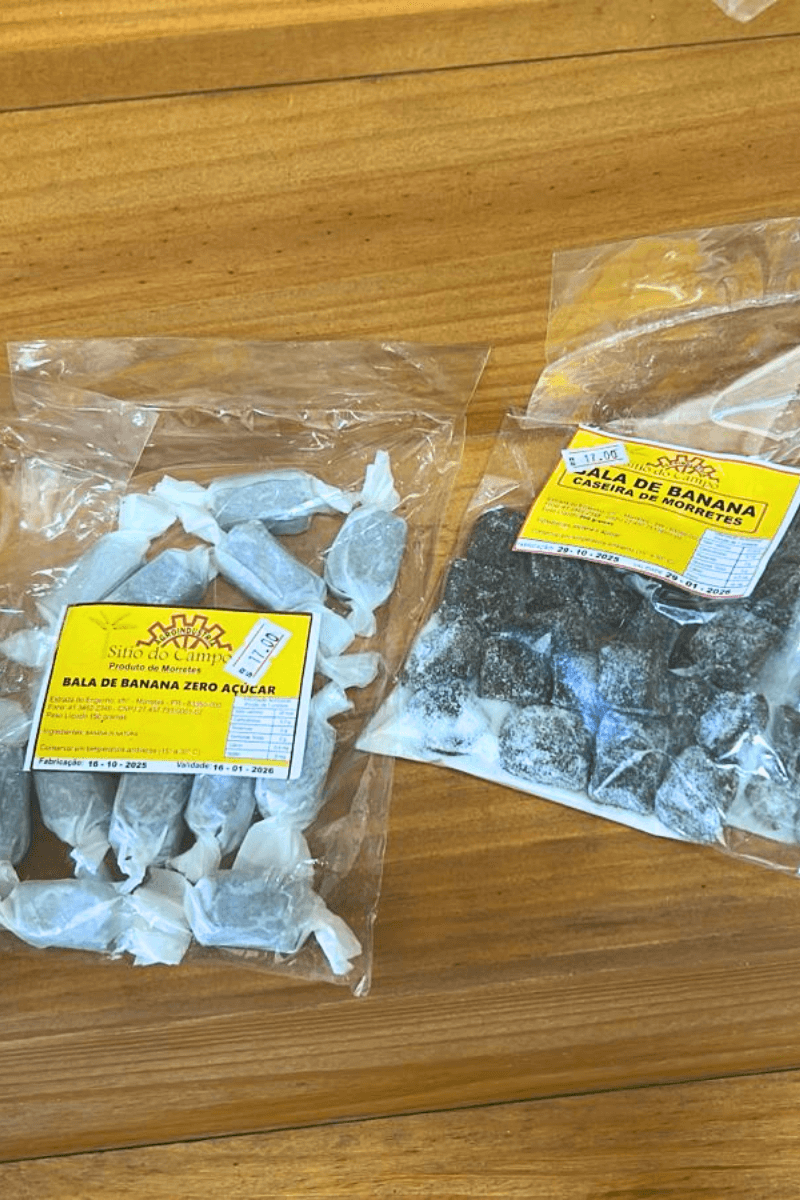 uas embalagens de balas de banana sobre superfície de madeira: à esquerda a versão Zero Açúcar (150g) e à direita a Caseira de Morretes (200g), ambas com rótulo amarelo.