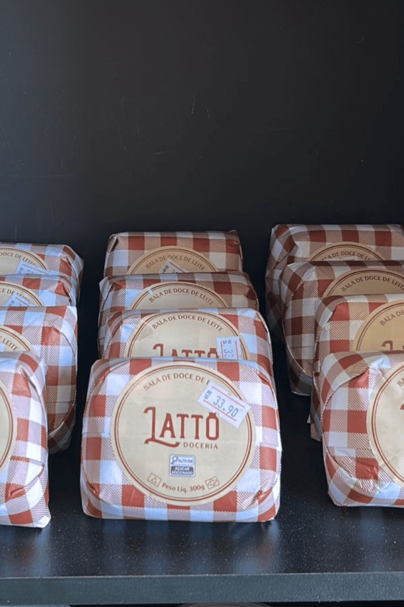 Pacotes de Bala de Doce de Leite da marca Lattô Doceria, peso líquido 300g, com embalagem em padrão xadrez marrom e branco e etiqueta redonda central.