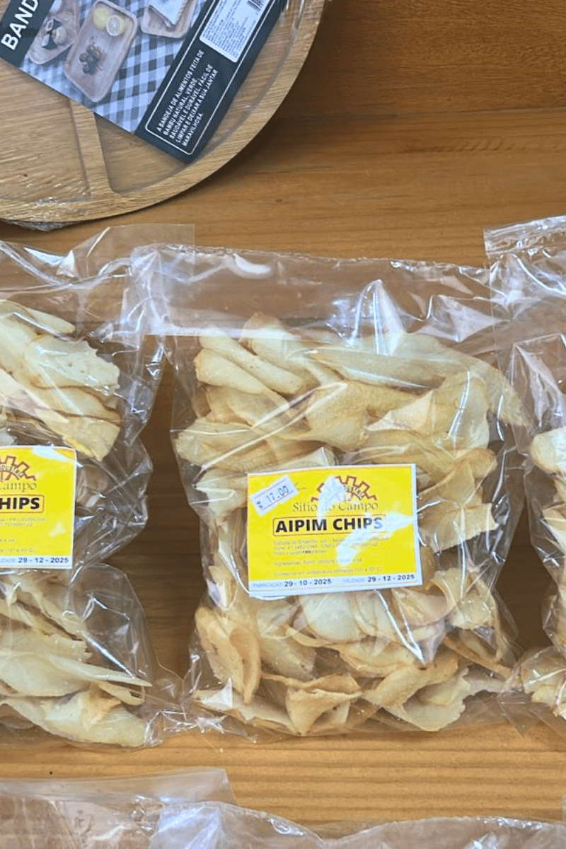 Embalagem transparente de Aipim Chips Sítio do Campo, exibindo lâminas de mandioca fritas e douradas com rótulo amarelo central.