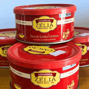 Empilhamento de latas vermelhas de Goiabada Zélia de Ponte Nova - MG, destacando o rótulo "Doce de Goiaba Cremoso" e a tradição desde 1950.