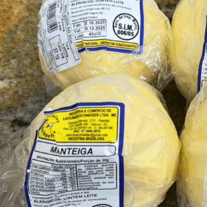 Três unidades de Manteiga Bola artesanal da Laticínios Schneider embaladas em plástico transparente sobre balcão, destacando o rótulo amarelo e selo de inspeção.