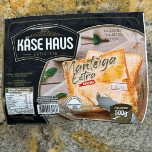 Embalagem de 500g de Manteiga Extra com Sal da marca Käse Haus, com imagem ilustrativa de manteiga sobre uma torrada, selo de inspeção S.I.E. 931 e indicação de produção em Santa Catarina.