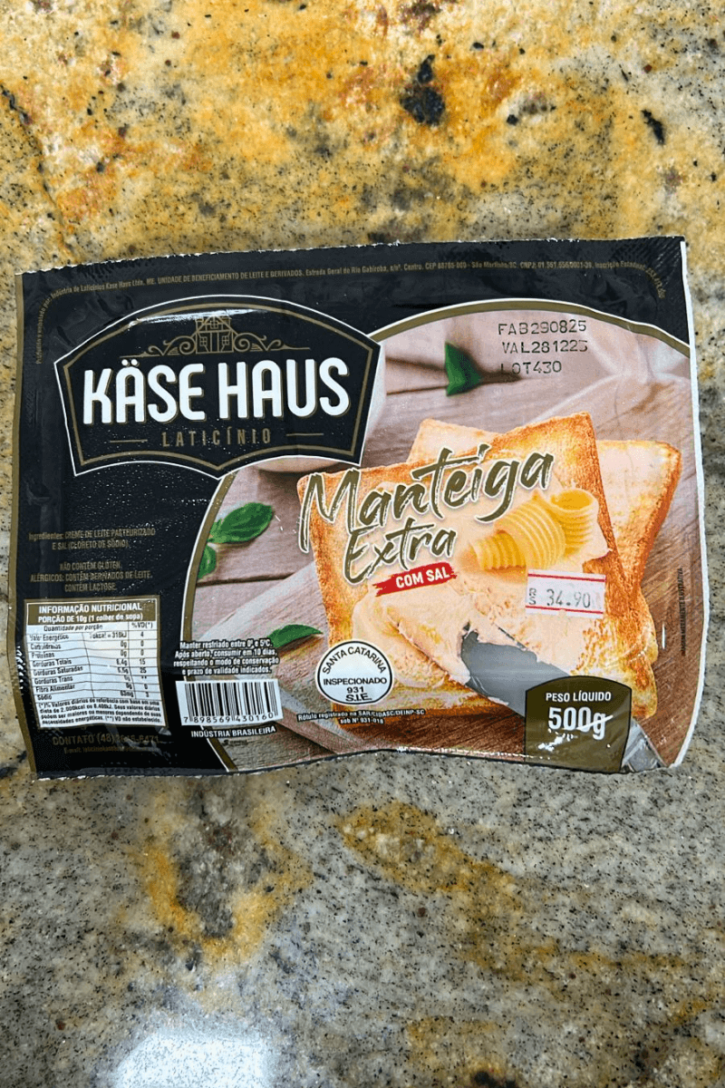 Embalagem de 500g de Manteiga Extra com Sal da marca Käse Haus, com imagem ilustrativa de manteiga sobre uma torrada, selo de inspeção S.I.E. 931 e indicação de produção em Santa Catarina.