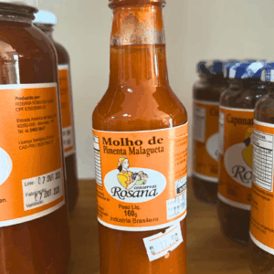 Frasco de plástico transparente com bico dosador vermelho, contendo Molho de Pimenta Malagueta Rosana de 160g, destacando a cor laranja vibrante.