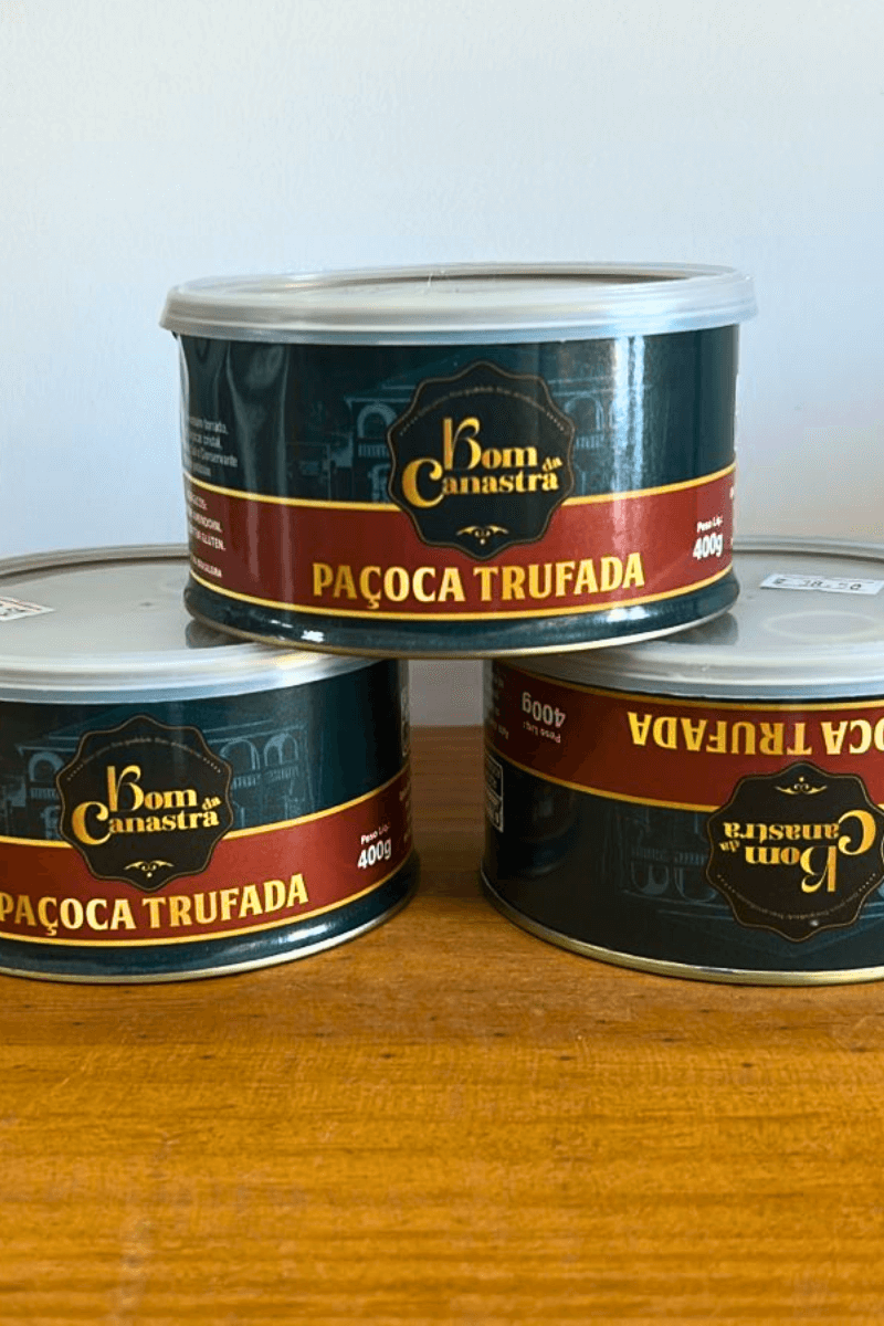 Três potes de Paçoca Trufada Bom da Canastra de 400g empilhados; a embalagem possui uma faixa bordô com letras douradas destacando o nome do produto.