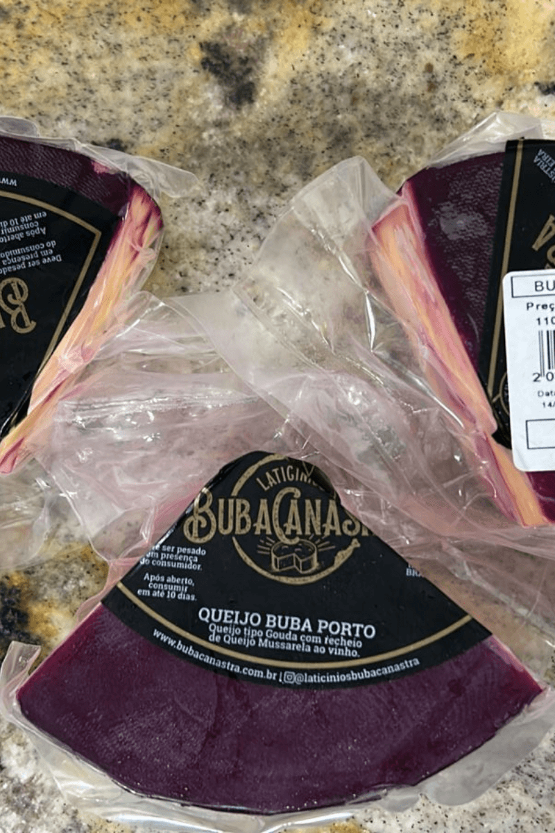 Três pedaços de Queijo Buba Porto embalados a vácuo, mostrando a base de queijo tipo Gouda com recheio interno de mussarela ao vinho tinto.