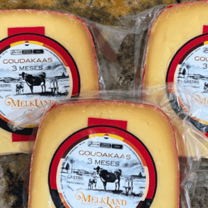 Peça de Queijo Goudakaas da Melkland, embalada a vácuo, com rótulo circular verde escuro e dourado destacando o moinho holandês, símbolo da tradição de Castro-PR.
