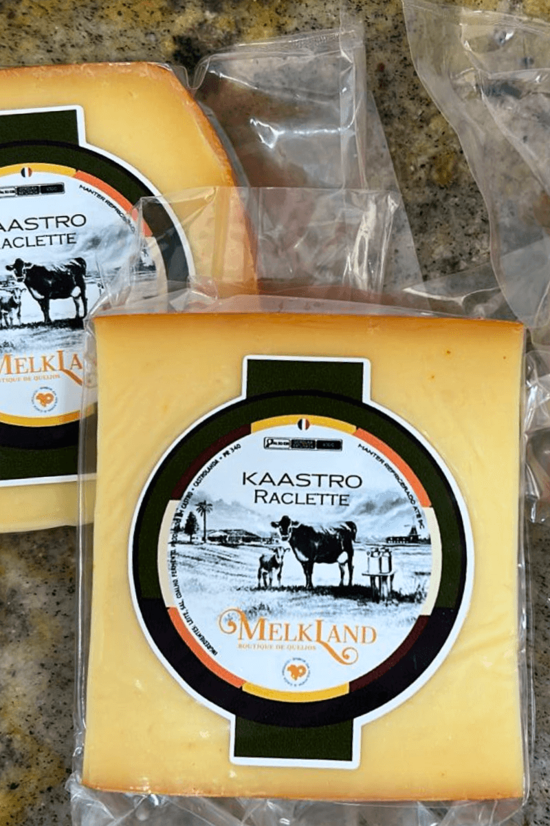 Peças de Queijo Kaastro Raclette da marca Melkland, embaladas a vácuo, com rótulo circular verde e laranja apresentando a ilustração de uma vaca e o nome do produto.