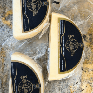Três pedaços de Queijo Minas Canastra Artesanal em formato de meia-lua, embalados a vácuo com rótulo azul e dourado da Laticínios Buba Canastra.
