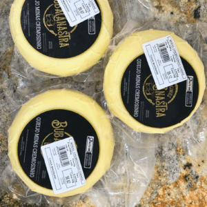 Três unidades de Queijo Minas Cremosinho Canastra embaladas a vácuo sobre bancada de granito, exibindo rótulo preto com informações nutricionais.