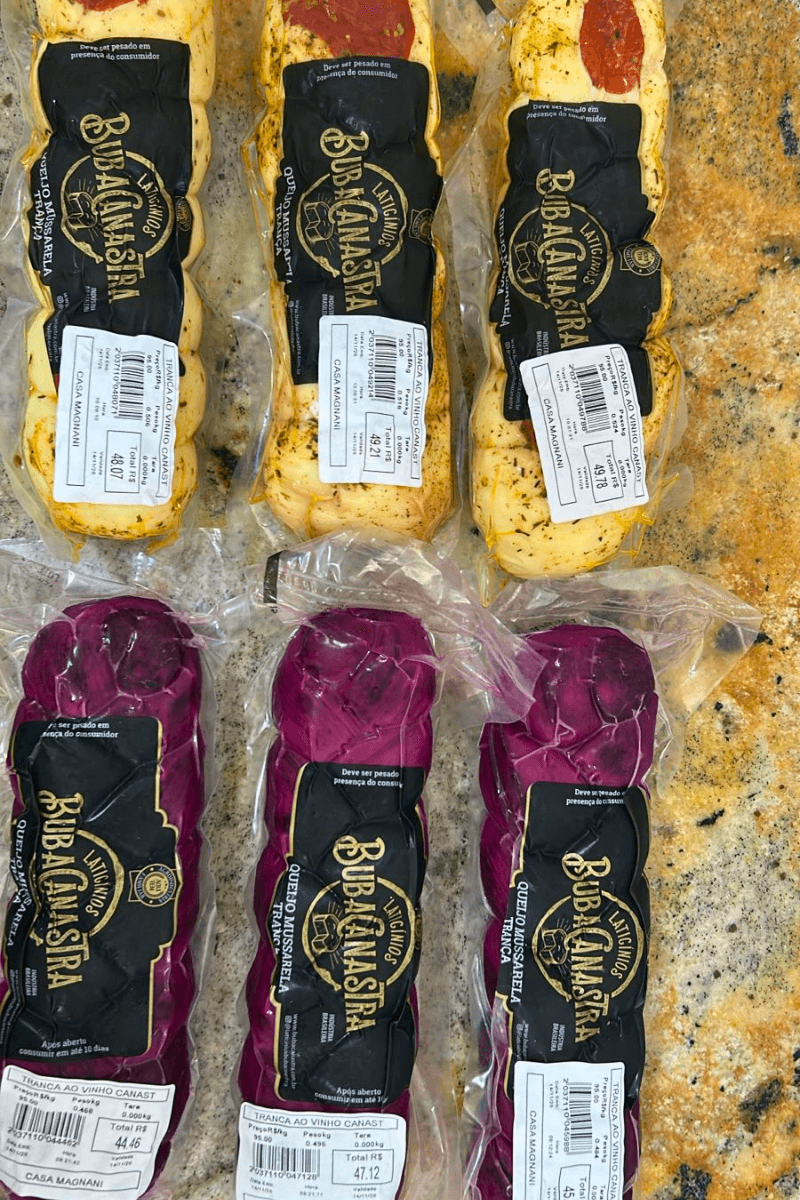 Variedade de Queijo Mussarela Trança BubaCanastra, incluindo versões banhadas ao vinho e versões com tomate seco e ervas, embaladas individualmente a vácuo.