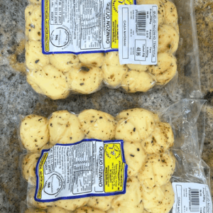 Duas embalagens de Queijo Nozinho Temperado da Laticínios Schneider sobre superfície de granito, mostrando os nozinhos com orégano e ervas.
