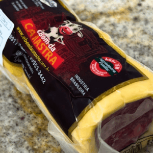 Peça de Queijo Provolone recheado com salame da marca Bom da Canastra em embalagem a vácuo, destacando o rótulo preto e vermelho com a ilustração de uma vaca sorridente.