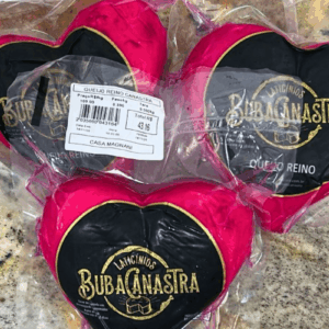Três unidades de Queijo Reino Canastra BubaCanastra em formato de coração, com casca magenta e embaladas a vácuo sobre bancada de granito.