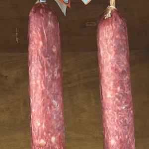 Duas peças de Salame Colonial artesanal da Embutidos São Francisco penduradas, exibindo a textura da cura e etiquetas de inspeção S.I.M.