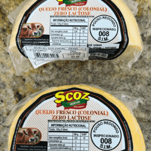 Duas peças fracionadas de Queijo Colonial Zero Lactose da marca Scoz, embaladas a vácuo, com rótulo branco e laranja destacando a indicação para dietas com restrição de lactose e o selo S.I.M. 008.