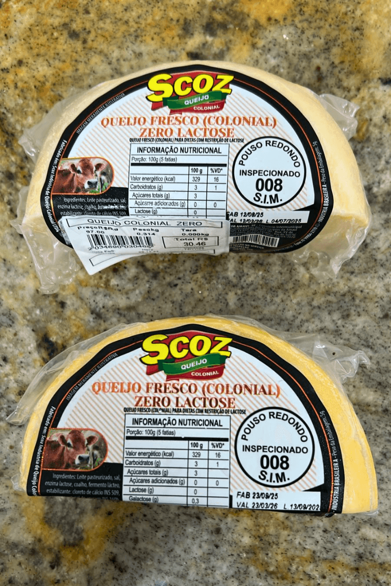 Duas peças fracionadas de Queijo Colonial Zero Lactose da marca Scoz, embaladas a vácuo, com rótulo branco e laranja destacando a indicação para dietas com restrição de lactose e o selo S.I.M. 008.
