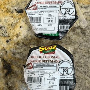 Peças fracionadas de Queijo Colonial Sabor Defumado da marca Scoz, embaladas a vácuo, com casca levemente dourada e rótulo destacando o selo de inspeção S.I.M. 008 de Pouso Redondo-SC.