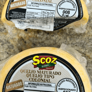 Duas peças fracionadas de Queijo Maturado Tipo Colonial Scoz, embaladas a vácuo, com rótulo destacando a inspeção S.I.M. 008 de Pouso Redondo e informações nutricionais.