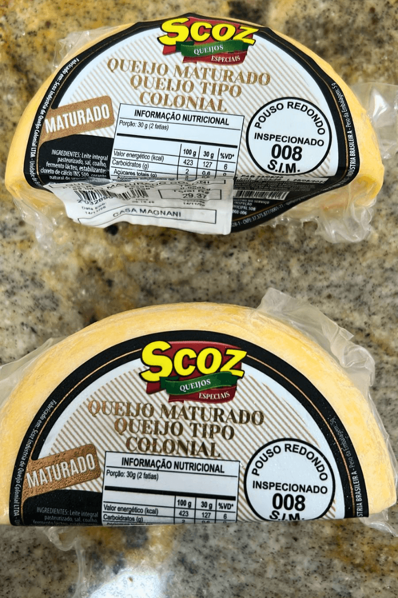 Duas peças fracionadas de Queijo Maturado Tipo Colonial Scoz, embaladas a vácuo, com rótulo destacando a inspeção S.I.M. 008 de Pouso Redondo e informações nutricionais.