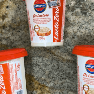 Copo de 150g de Requeijão Cremoso Catupiry Zero Lactose, embalagem branca e vermelha com a inscrição "Lacto Zero" e ícone indicando enriquecimento com vitaminas A, K, E e D.